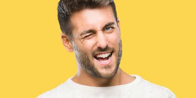 Cute young man with a beard wearing a white tshirt winking cheekily