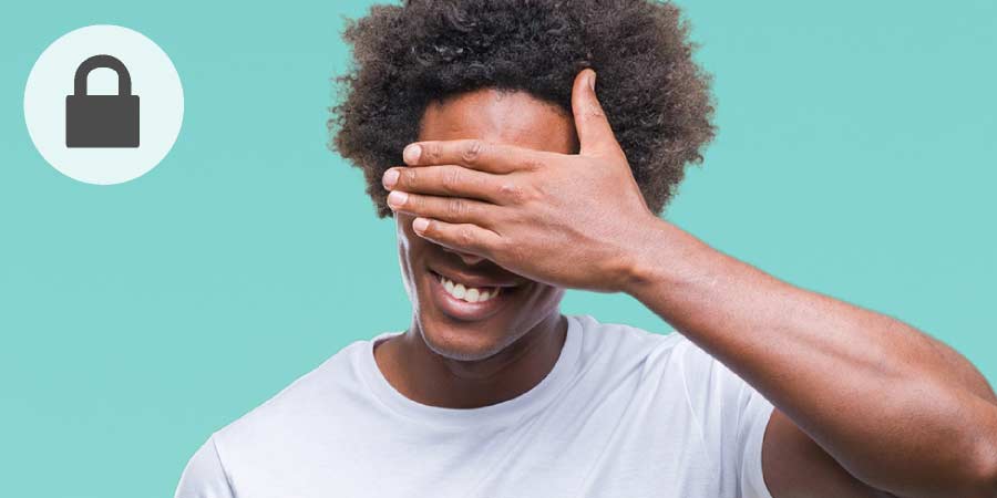 Man wearing white tshirt laughing and covering his eyes with his hand.